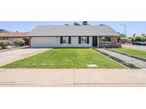 Charming single-story home featuring a lush green lawn and tidy landscape at 1021 S Almar Cir, Mesa, AZ 85204