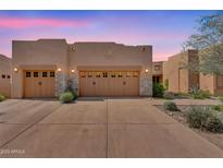Inviting home exterior features a three car garage with stone accents and desert landscaping at 13450 E Via Linda -- # 2022, Scottsdale, AZ 85259