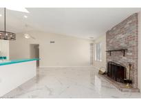 Bright living room featuring a brick fireplace, white marble floors, and modern lighting at 643 W Medina Ave, Mesa, AZ 85210