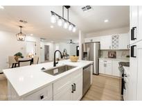 Bright kitchen boasts white cabinets, stainless steel appliances, quartz countertops and updated lighting at 1425 E Diamond St, Phoenix, AZ 85006