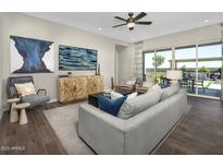 Bright living room featuring modern furniture, sleek ceiling fan, and sliding glass doors to outdoor patio at 14825 W Whitehorn Way, Surprise, AZ 85387