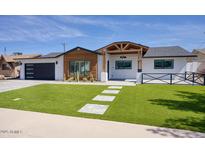Charming single-story home with modern black garage and manicured front yard at 8318 E Sells Dr, Scottsdale, AZ 85251