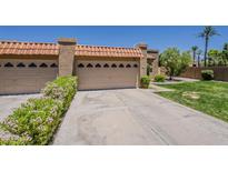 Inviting home featuring a three car garage, terra cotta roof, desert landscaping, and an expansive driveway at 9196 E Evans Dr, Scottsdale, AZ 85260