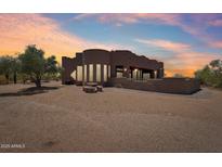 Custom home featuring unique architectural details, spacious outdoor area, and desert landscaping under a vibrant sky at 10600 E Cordova St, Gold Canyon, AZ 85118