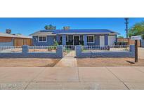 Charming single-story home with a blue exterior, solar panels, and a secure fenced yard at 13913 N 2Nd Ave, El Mirage, AZ 85335