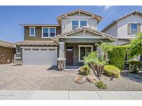 Charming two-story home featuring a brick driveway, a two-car garage, and a landscaped front yard with small palm trees at 3422 E Strawberry Dr, Gilbert, AZ 85298