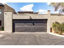 Two car garage with a black door and stucco siding, with an attached front parking area at 618 E Manzanita Pl, Phoenix, AZ 85020