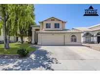 Charming two-story home featuring a neutral color scheme, tile roof, and a well-manicured front lawn at 869 W Shellfish Dr, Gilbert, AZ 85233