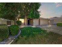 Charming home featuring a well-maintained lawn, mature trees, and a convenient two-car garage at 13633 W Alvarado Dr, Goodyear, AZ 85395