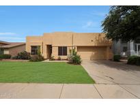 Attractive tan home features a two-car garage, green lawn, and desert landscaping at 2229 S 82Nd Ln, Phoenix, AZ 85043