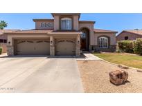 Two-story home with a three-car garage, desert landscaping, and a covered front porch at 3089 E Indigo Bay Dr, Gilbert, AZ 85234
