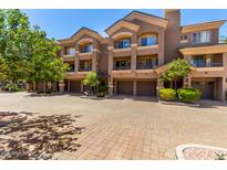 Stylish multi-level townhome with a brick-paved drive, multiple garages, and desert landscaping under a bright blue sky at 4465 E Paradise Village S Pkwy # 1224, Phoenix, AZ 85032