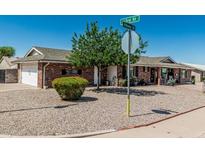 Corner lot single-story brick home featuring desert landscaping with green tree and shrubbery at 6247 E Albany St, Mesa, AZ 85205