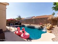 Backyard features a pool with a waterfall feature and patio furniture for entertaining at 7826 W Mcrae Way, Glendale, AZ 85308