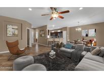 Inviting living room featuring a modern ceiling fan, tile flooring, and an open-concept layout to the kitchen and dining area at 16525 W Tranquility Ln, Surprise, AZ 85387