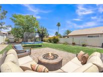 Inviting backyard featuring a fire pit, trampoline, and well-maintained lawn at 17425 N 1St Dr, Phoenix, AZ 85023