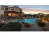 Outdoor pool with desert landscaping, lighting, and a covered patio creates a backyard oasis at 18121 E San Luis Dr, Gold Canyon, AZ 85118