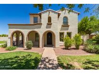 Charming two-story home featuring a stucco facade, arched entryways, and a well-manicured front yard with lush landscaping at 20409 W Thayer St, Buckeye, AZ 85396