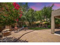 Paver-covered backyard features a built-in fireplace, seating, and a lush green lawn at 5208 W Straight Arrow Ln, Phoenix, AZ 85083