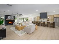 Bright open-plan living space featuring a fireplace, kitchen with bar seating, and neutral-toned decor at 5937 E Corrine Dr, Scottsdale, AZ 85254
