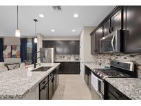 Modern kitchen featuring granite countertops, stainless steel appliances, and dark wood cabinetry at 12152 W Briles Rd, Peoria, AZ 85383