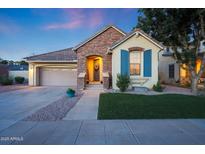 Charming single-story home featuring a brick facade, well-manicured lawn, and inviting front entrance at dusk at 13295 N 153Rd Ln, Surprise, AZ 85379