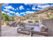 Inviting stone patio featuring a wicker sectional, lounge chairs, and stunning desert mountain views at 25555 N Windy Walk Dr # 69, Scottsdale, AZ 85255