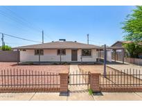 Charming single-story home with red rock front yard and brick and iron fence at 2721 W Luke Ave, Phoenix, AZ 85017