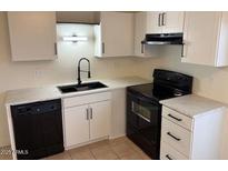 Bright kitchen features white cabinets, black appliances, and updated countertops at 3120 N 67Th Ln # 17, Phoenix, AZ 85033