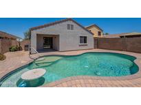 Backyard view of a refreshing pool featuring a step entry, seating table, and well-maintained brick border at 37053 W Amalfi Ave, Maricopa, AZ 85138