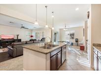 Bright kitchen features a granite countertop island with a stainless steel sink and pendant lighting at 4032 S Santa Rita Pl, Chandler, AZ 85249