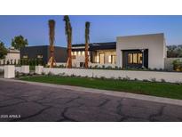 Modern home exterior with a manicured lawn, palm trees and a sleek design at 6303 E Via Estrella Ave, Paradise Valley, AZ 85253
