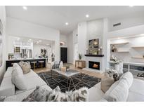 Bright living room features a fireplace, light hardwood floors, and opens to a modern kitchen with stainless steel appliances at 8965 E Maple Dr, Scottsdale, AZ 85255
