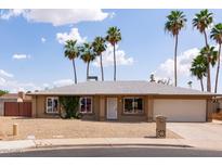 Charming single-story home featuring a well-maintained yard, palm trees, and an attached two-car garage at 929 W Knowles Cir, Mesa, AZ 85210