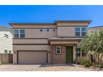 Two-story home featuring neutral stucco, brown trim, brick accents, a 2-car garage and green door, offering a modern design at 1879 W 23Rd Ave, Apache Junction, AZ 85120
