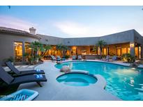 Inviting backyard pool and spa surrounded by lush landscaping and lounge chairs at dusk at 22020 N Church Rd, Scottsdale, AZ 85255