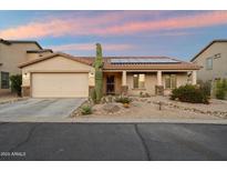 Charming single-story home featuring desert landscaping, a two-car garage, and solar panels on the roof at 2487 S Conestoga Rd, Apache Junction, AZ 85119