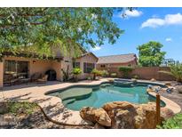 Backyard oasis with a freeform pool, rock features, and lush landscaping provides a relaxing outdoor space at 24886 W Huntington Dr, Buckeye, AZ 85326