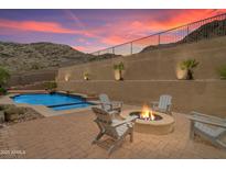 Beautiful backyard with a pool, fire pit, and chairs, set against the backdrop of a desert mountain at 2722 W Hiddenview Dr, Phoenix, AZ 85045