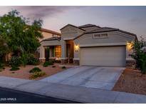 Charming single-story home featuring a two-car garage and welcoming desert landscaping at dusk at 29819 W Whitton Ave, Buckeye, AZ 85396