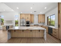 Bright kitchen with natural wood cabinets, stainless appliances, and a large center island with a marble countertop at 31107 N 72Nd Pl, Scottsdale, AZ 85266