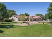 Charming single-story home featuring a landscaped front yard with mature trees and desert landscaping at 3357 N Ashbrook E St, Mesa, AZ 85213
