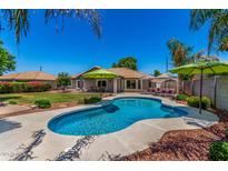 Sparkling pool and lush backyard oasis featuring an outdoor dining space and shade umbrellas at 3619 E Thornton Ave, Gilbert, AZ 85297