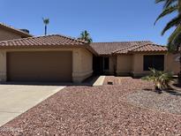 Charming single-story home featuring a tile roof, two car garage, and low maintenance rock landscaping at 4301 E Amberwood Dr, Phoenix, AZ 85048