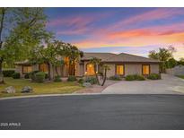 Beautiful single-story home with desert landscaping, tile roof, and a view of a colorful sunset at 9 E Los Arboles Cir, Tempe, AZ 85284