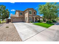 Beautiful two-story home featuring a two-car garage, well-manicured lawn, and a charming stone-accented entryway at 18045 W Rimrock St, Surprise, AZ 85388