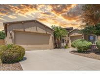 Inviting beige home featuring a two-car garage and manicured landscaping against a dramatic sky at 2554 E Honeysuckle Pl, Chandler, AZ 85286
