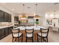 Spacious kitchen features an island with seating, stainless steel appliances, and stylish pendant lighting at 6069 E Ironwood Dr, Scottsdale, AZ 85266