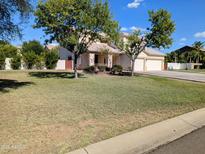 Charming two-story home with a well-maintained front yard and mature trees under a clear blue sky at 1015 S 132Nd St, Gilbert, AZ 85233
