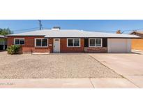 Charming brick home featuring a gravel front yard, white trim, and a single-car garage at 1028 W 5Th St, Mesa, AZ 85201